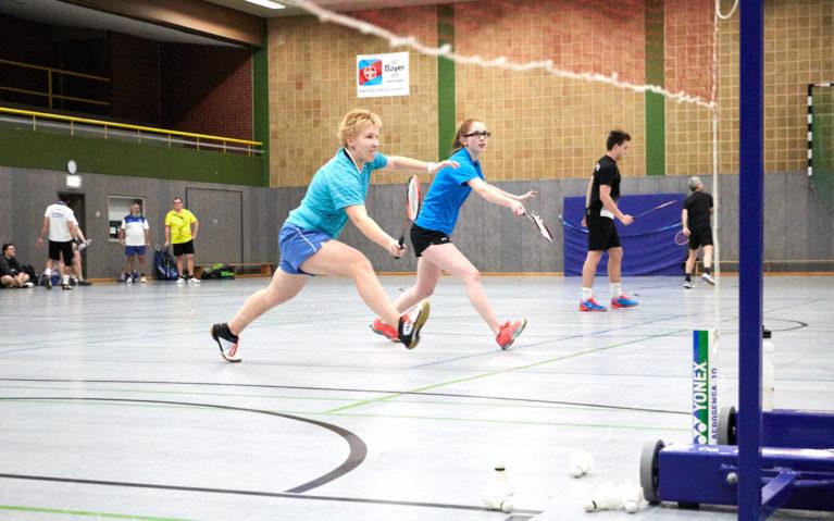 Zwei Badminton Spielerinnen machen einen Schritt nach vorne