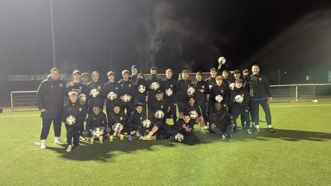 Fußballmannschaft posiert mit neuen Bällen
